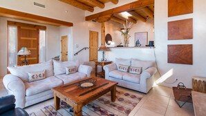 Un salon spacieux avec deux canapés blancs, une table basse en bois et un plafond rustique.