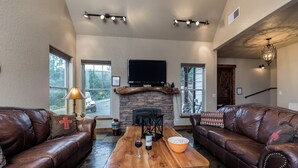 A cozy living room with leather sofas, a wooden coffee table, a fireplace, and a flat-screen TV. - Casa Oso Grande by Ruidoso Vacation Rentals (Ruidoso)