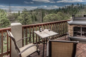 Eine Terrasse mit einem Steinkamin, einem Tisch mit zwei Weingläsern und einem Stuhl.
