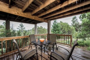 Eine überdachte Terrasse im Freien mit Holzgeländern, einem Tisch und Stühlen.