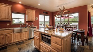 A spacious kitchen with wooden cabinets, a large island, and a dining area with outdoor seating. - Casa Oso Grande by Ruidoso Vacation Rentals (Ruidoso)