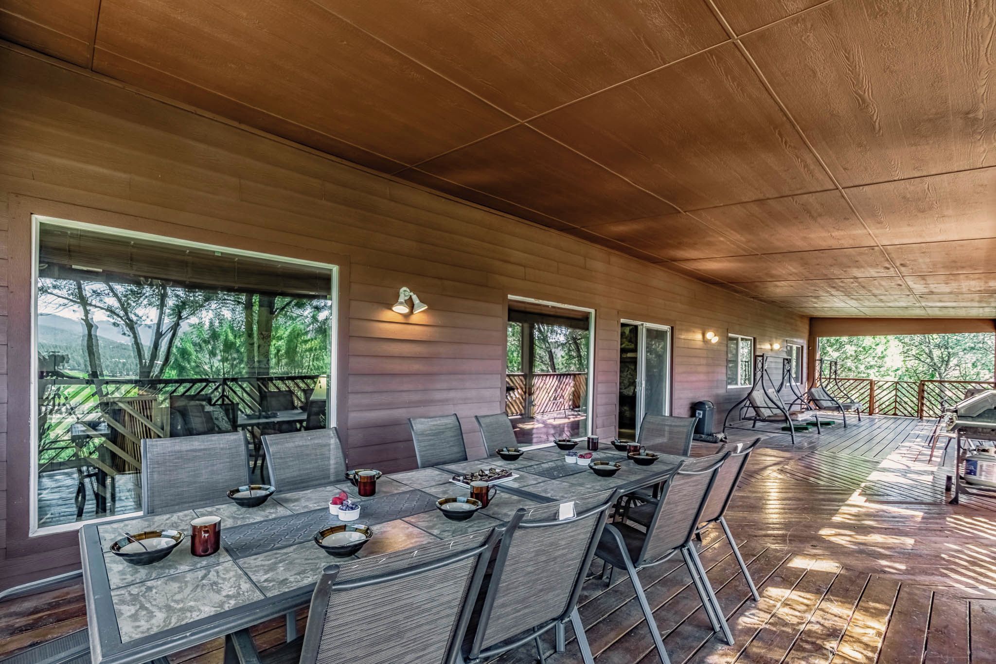 Un espacio de comedor al aire libre con techo, una mesa larga, sillas y una parrilla.