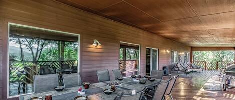 Un espacio de comedor al aire libre con techo, una mesa larga, sillas y una parrilla.
