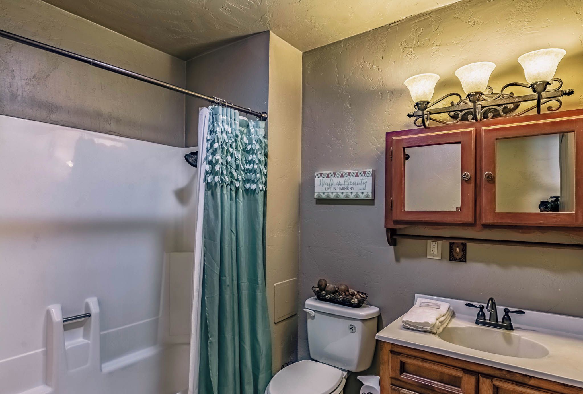 A bathroom with a shower, toilet, sink, and vanity.