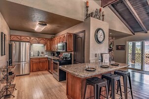 A spacious kitchen with wooden cabinets, stainless steel appliances, and a large island with bar stools.