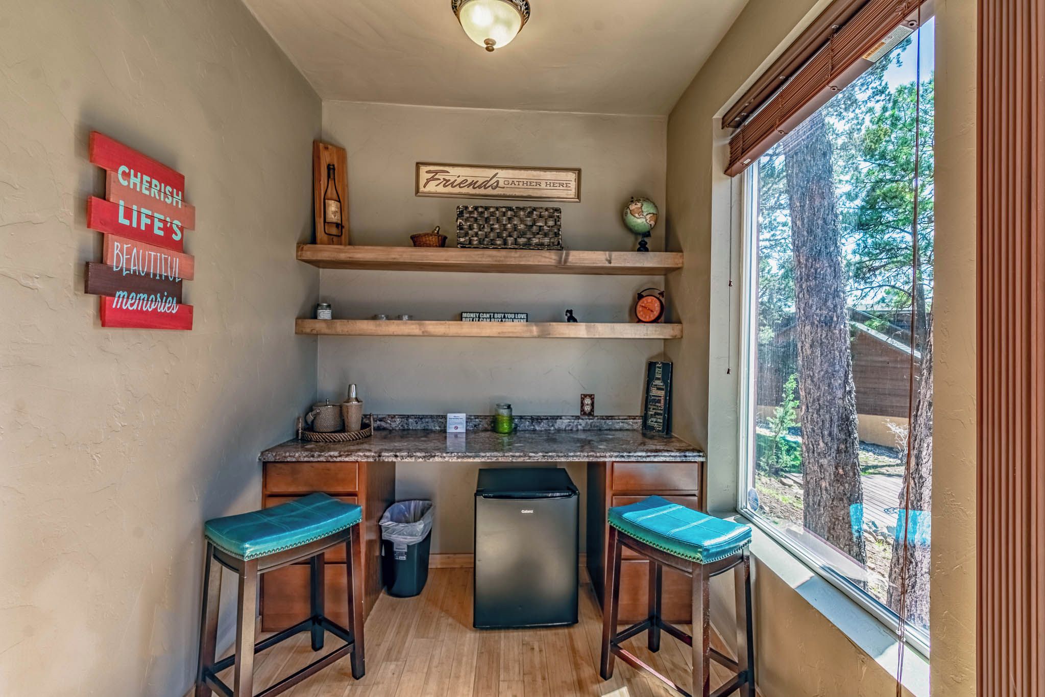 A compact kitchen with wooden shelves, a refrigerator, and two bar stools.