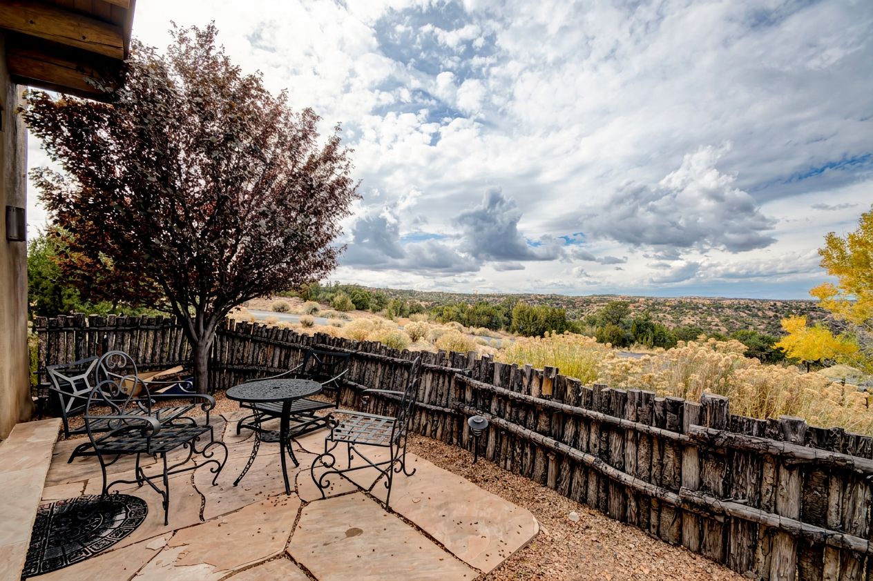 An outdoor patio with a wooden fence, a table, and chairs.