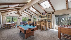 A spacious indoor recreational area with a pool table, foosball table, and seating.