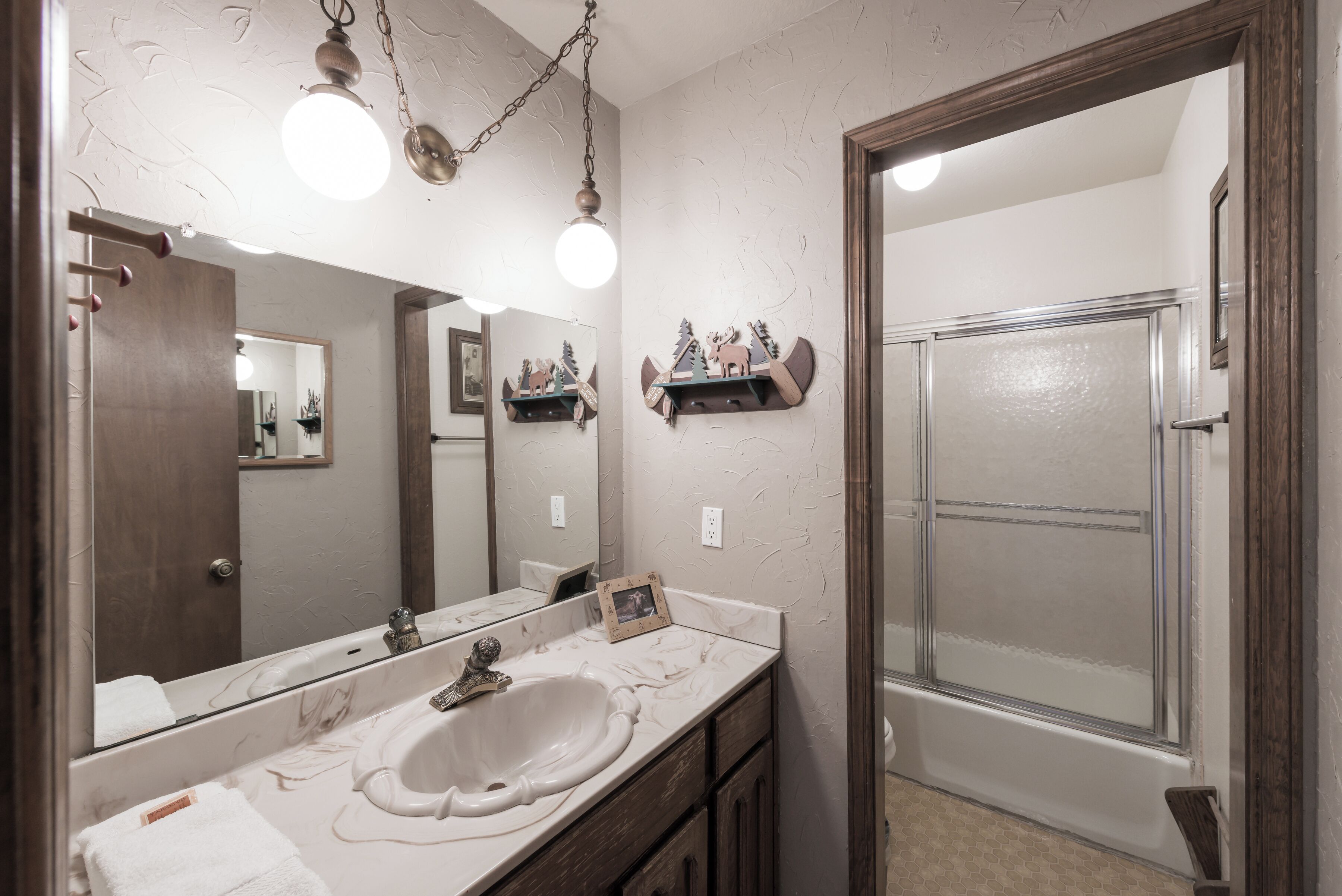 Een badkamer met een marmeren wastafel, een grote spiegel en een douche.