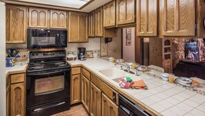 A kitchen with wooden cabinets, a black stove, a microwave, and a sink.