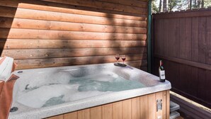 A wooden cabin with a hot tub and a bottle of wine on the deck. - Cowboy Cabin by Ruidoso Vacation Rentals (Ruidoso)