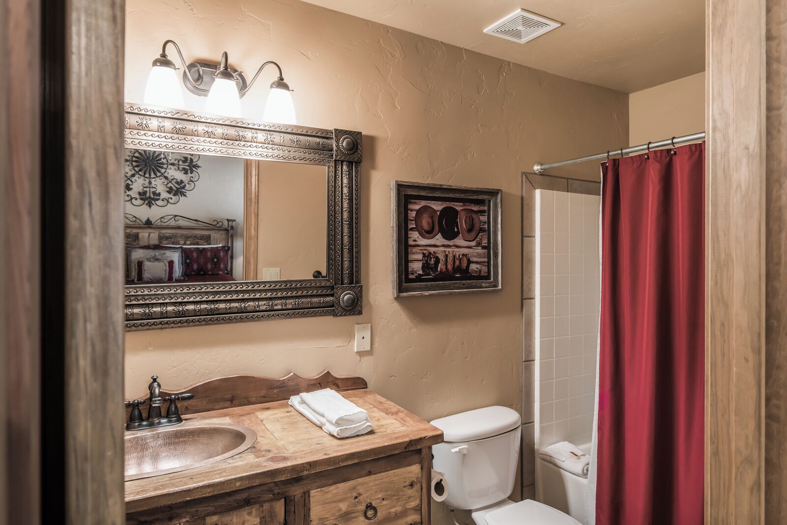 A bathroom with a wooden vanity, a large mirror, a toilet, and a shower curtain.