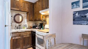 Eine kleine Küche mit Holzausbau, einem weißen Herd und einer Essecke mit einem Holztisch.