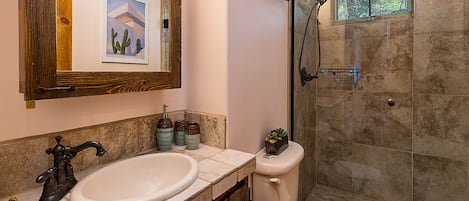 A bathroom with a double sink, a toilet, a shower, and a large mirror.