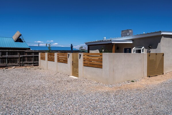 Uma casa moderna com acesso por caminho de pedras, cerca de madeira e telhado azul.