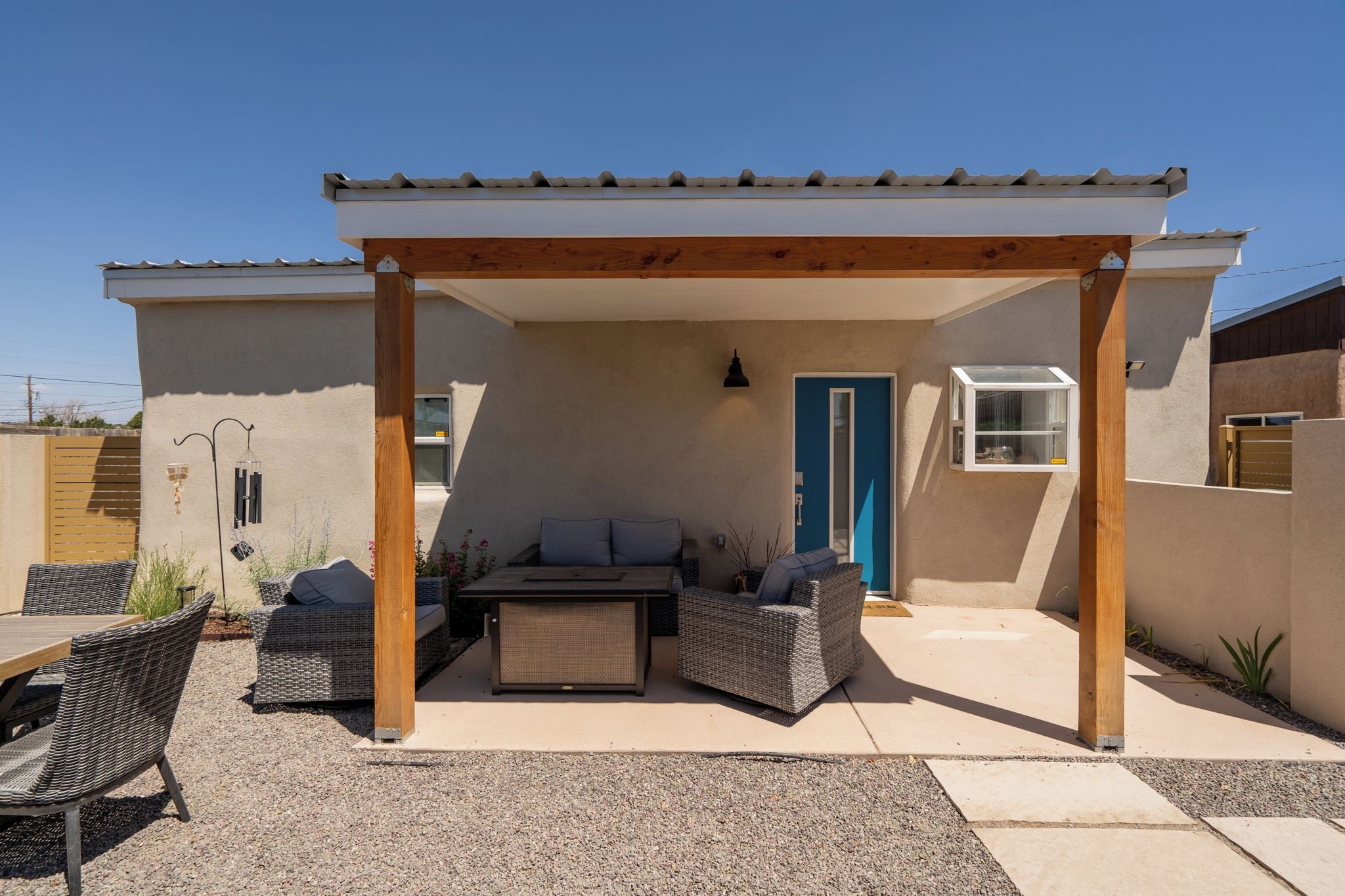 Un patio al aire libre con una pérgola, muebles de mimbre y una mesa.