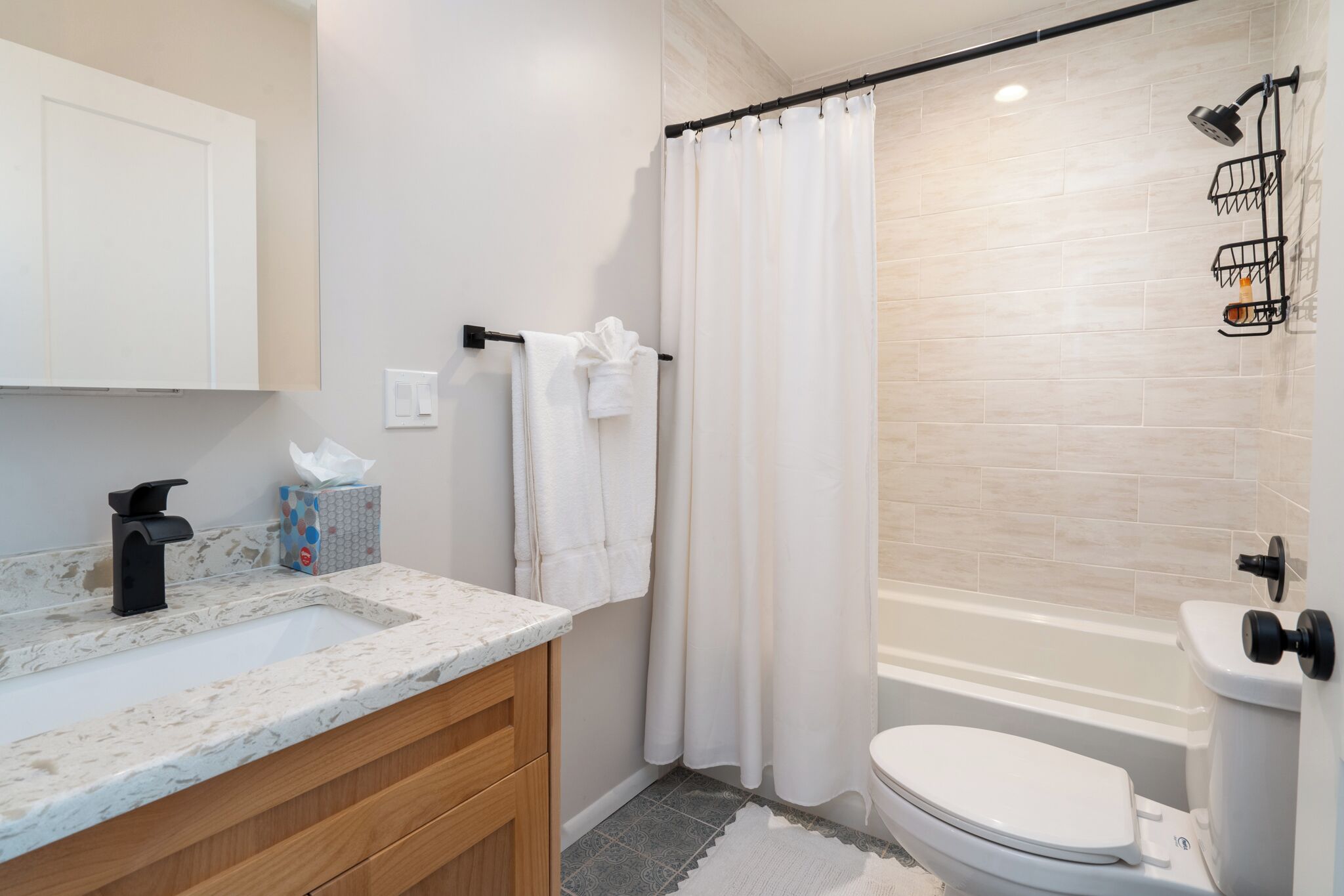 A bathroom with a sink, toilet, and shower area.