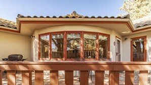 A covered outdoor area with a wooden deck, large windows, and a tiled roof. - DB Mountain by Ruidoso Vacation Rentals (Ruidoso)