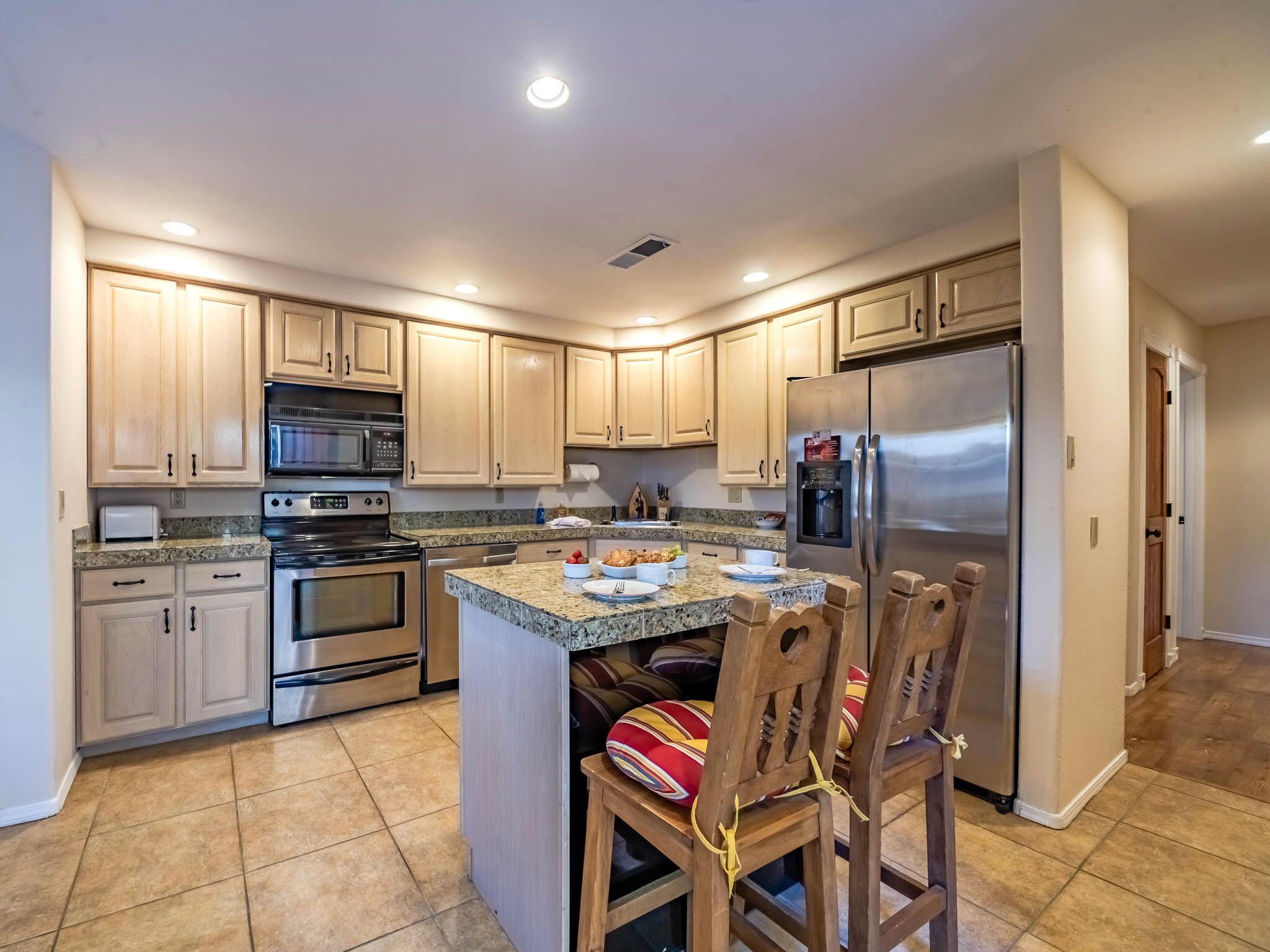 A kitchen with wooden cabinets, stainless steel appliances, and a granite countertop.