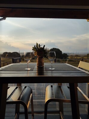 A table with two wine glasses and a vase of flowers, set against a scenic view. - Absolute Repose - Secluded Cottage (Stonewall)