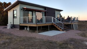 A modern house with a deck, a covered outdoor area, and a gravel driveway. - Absolute Repose - Secluded Cottage (Stonewall)