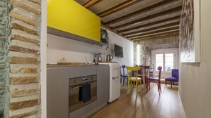Cozinha com forno embutido, geladeira e armário amarelo. Há uma área de jantar com mesa e cadeiras.