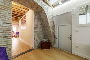A room with a wooden floor, a brick archway, a white door, and a small wooden chest.
