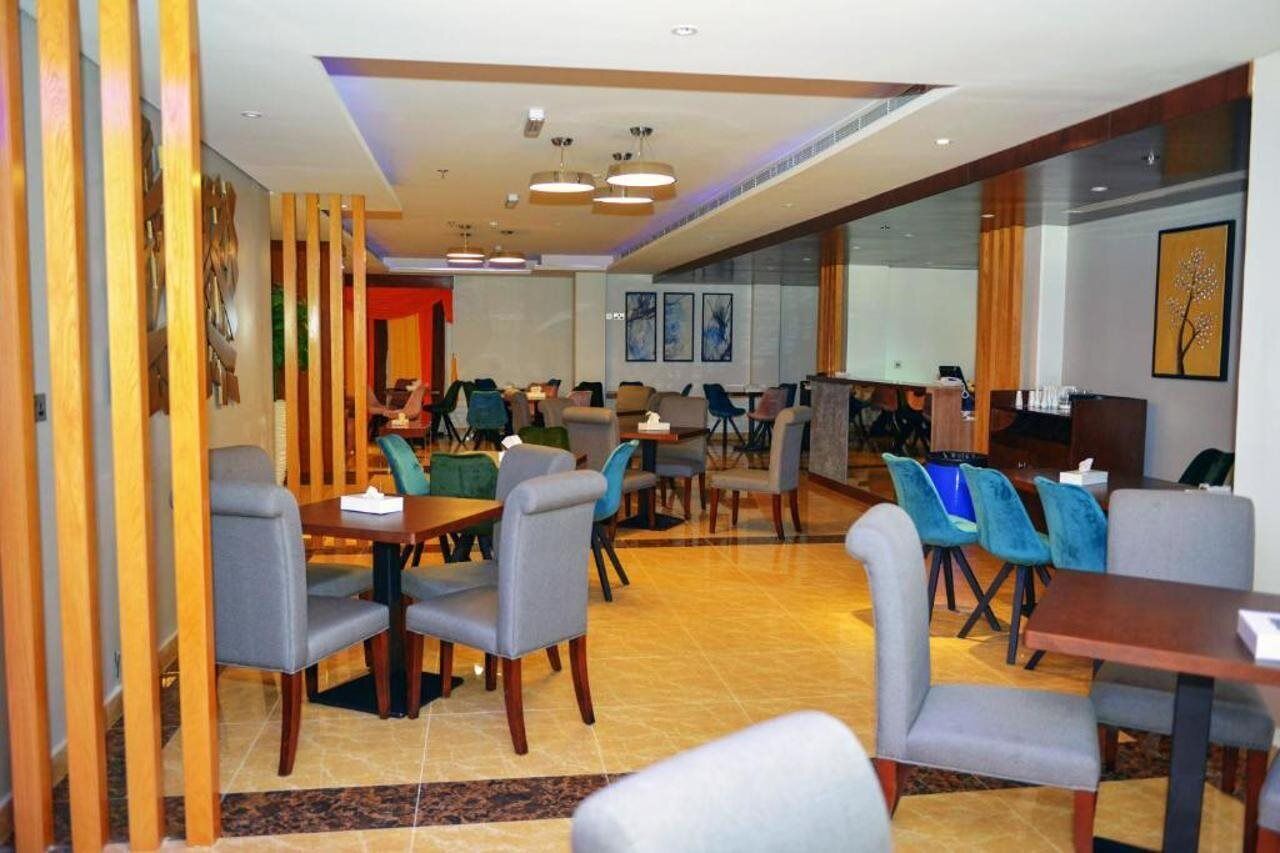 A hotel dining area with multiple tables and chairs, a bar, and artwork on the walls.