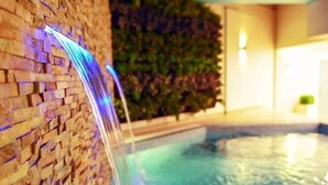 A pool with a brick wall and a waterfall feature. - Meshal Hotel And Spa (Manama)