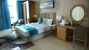 A hotel room with a bed, desk, chair, and a large mirror. - Meshal Hotel And Spa (Manama)