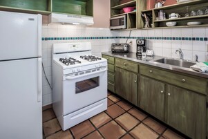 Uma cozinha com fogão branco, micro-ondas, torradeira e pia.