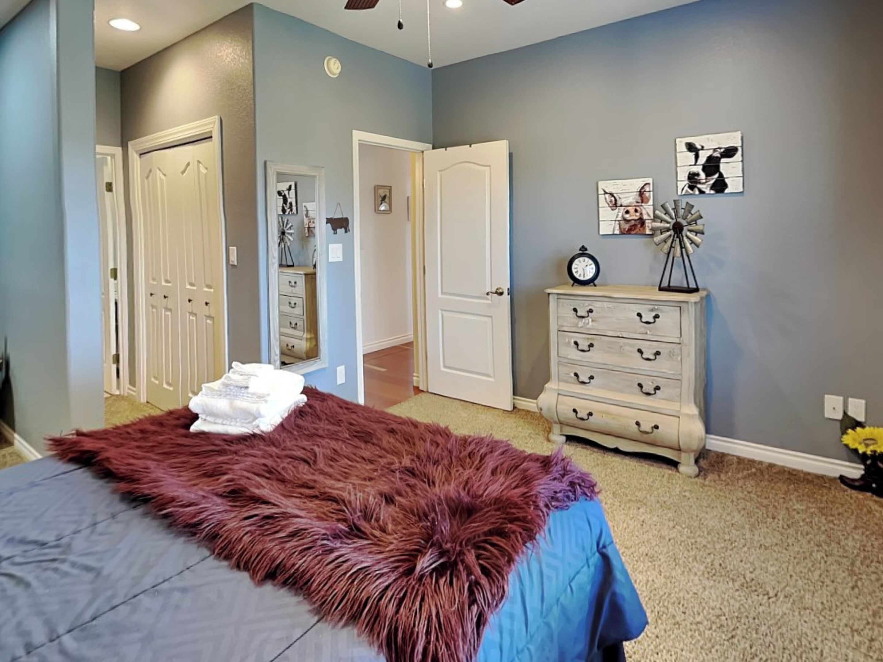 A bedroom with a bed, a dresser, and a door leading to another room.