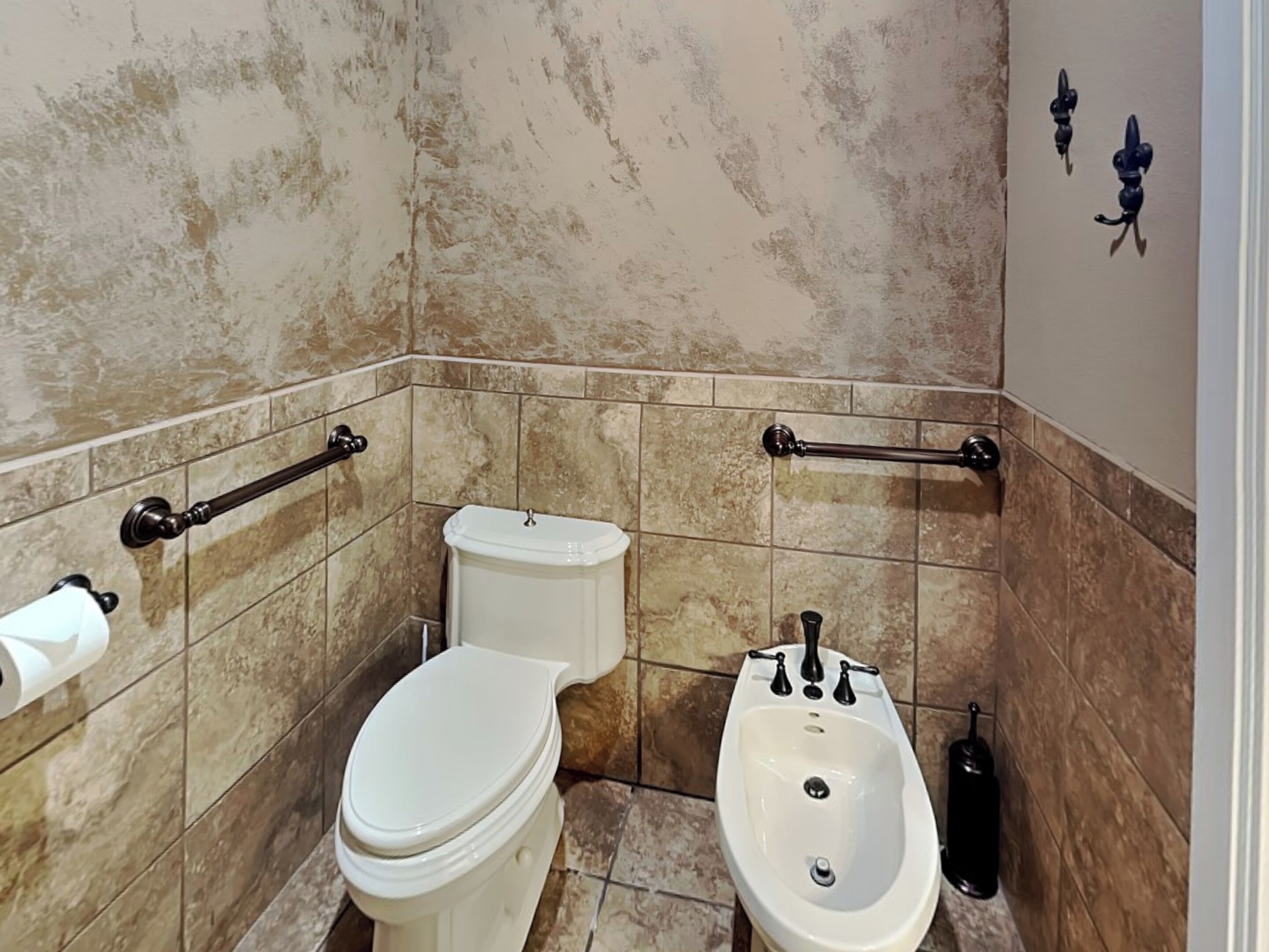 A bathroom with a toilet, bidet, and towel rack.