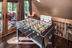 Relax in a stylish space with a foosball table, large window, and comfortable chair.