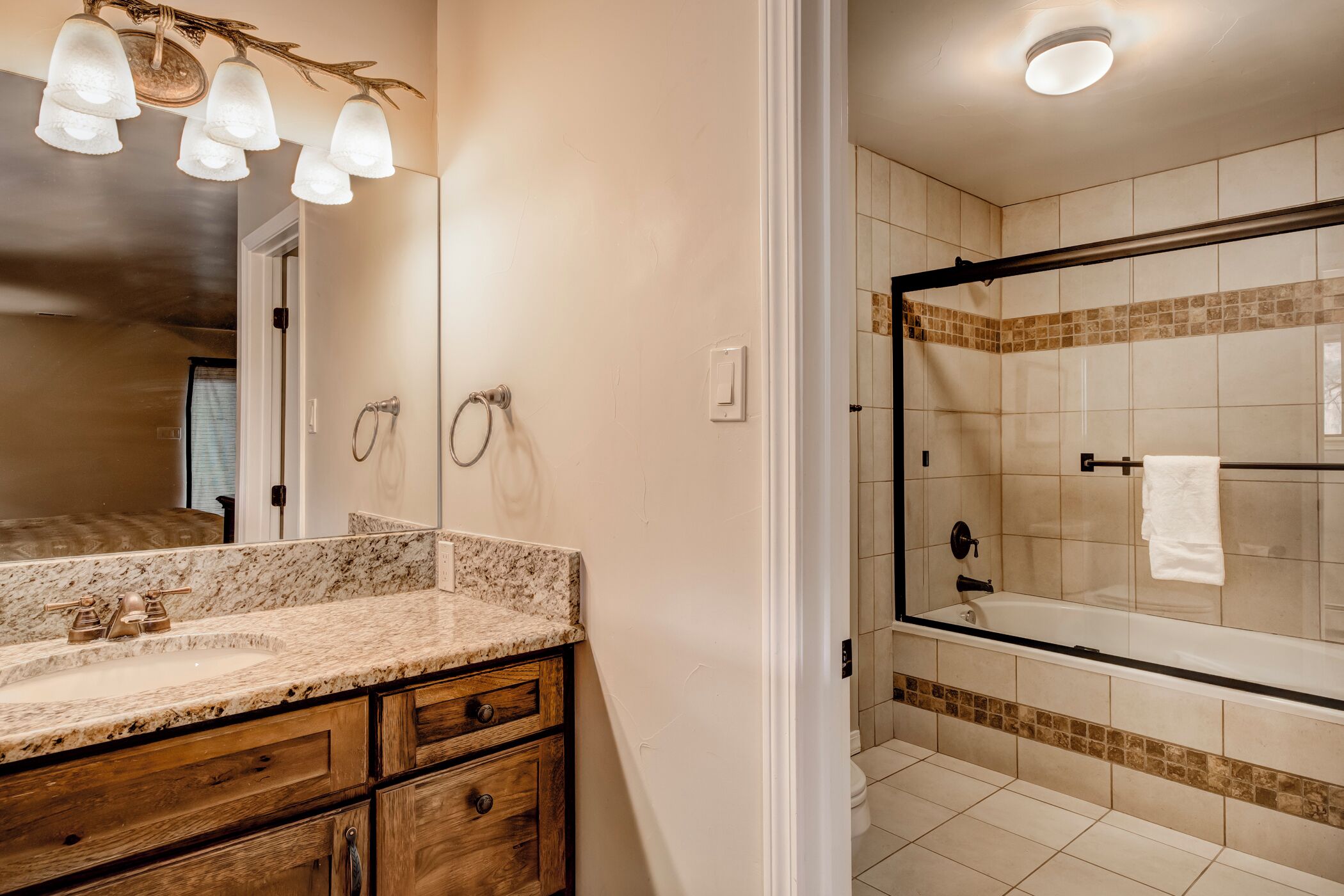 A bathroom with a marble vanity, a glass shower enclosure, and a tiled floor.