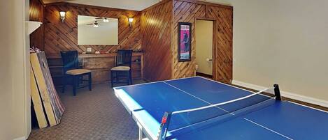 A ping pong table in a room with wooden walls and a ceiling fan.