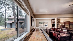 Ein Shuffleboardtisch in einem Wohnzimmer mit Blick auf ein Haus und Bäume.