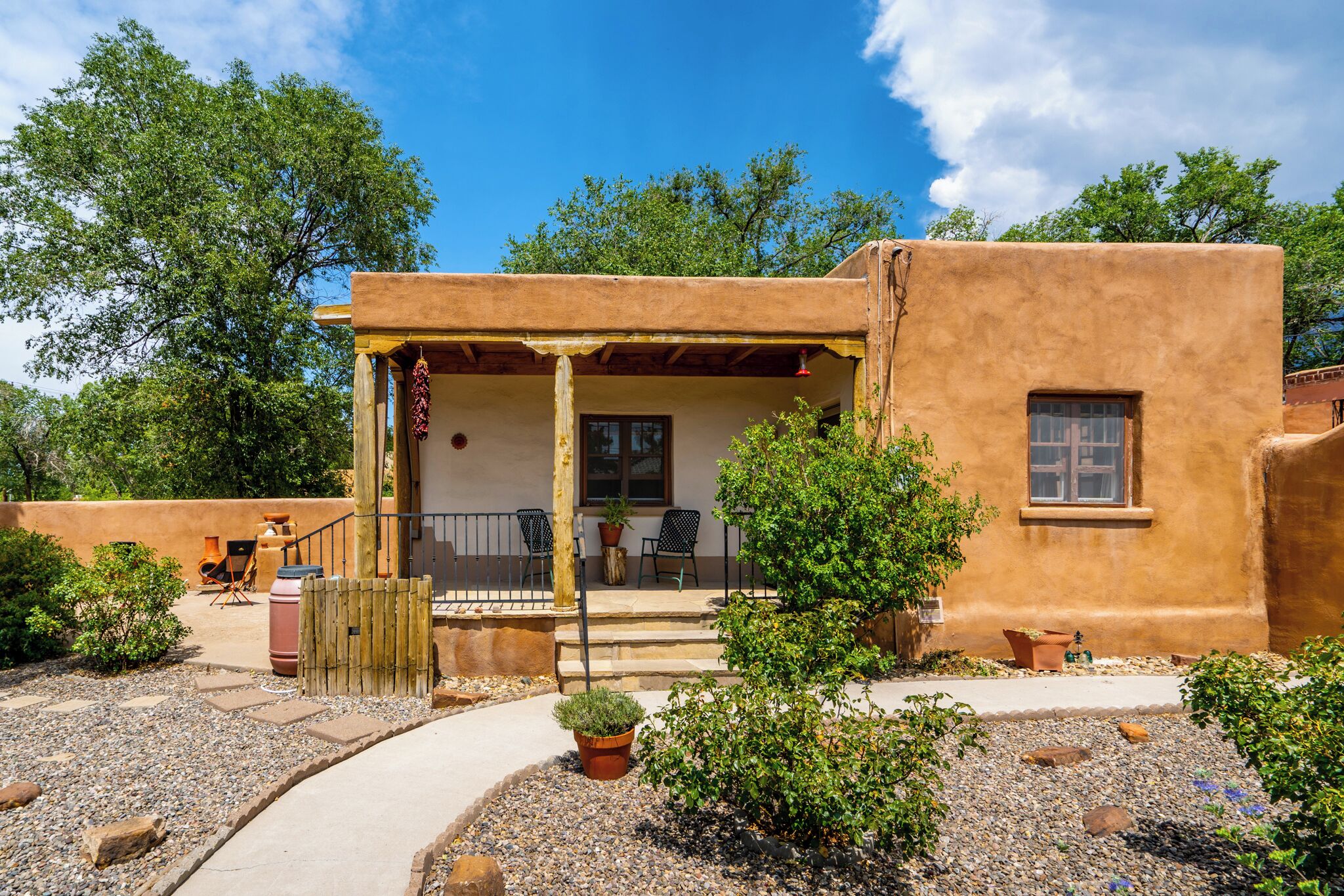 A rustic building with a covered porch, outdoor seating, and a garden area.