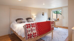Een slaapkamer met een bed, nachtkastje, lamp en raam.
