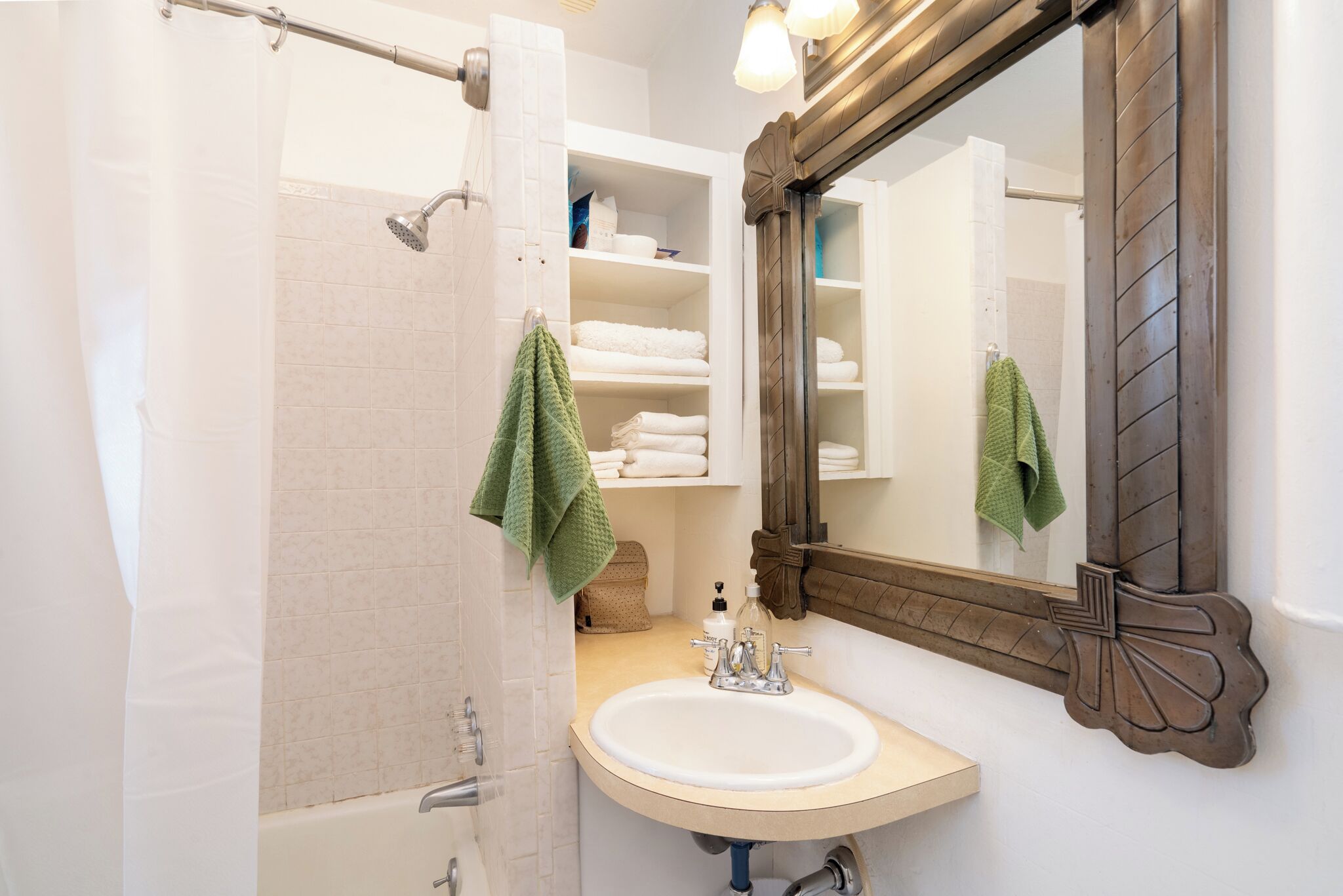 Baño con ducha, lavamanos y espejo.
