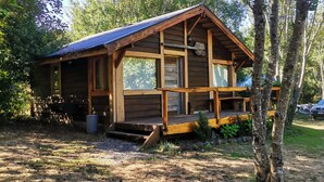Una cabaña de madera con un porche, rodeada de árboles.