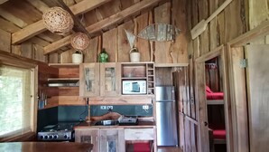 Una cocina rústica con paredes de madera, estufa, pileta y refrigerador.
