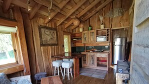 Interior rústico de una cabaña de madera con comedor, barra y cocina.