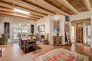A spacious room with a wooden dining table, chairs, and a large rug.