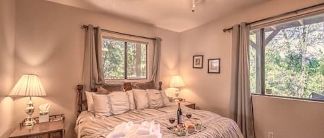 A bedroom with a bed, two bedside tables, a ceiling fan, and a window with curtains.