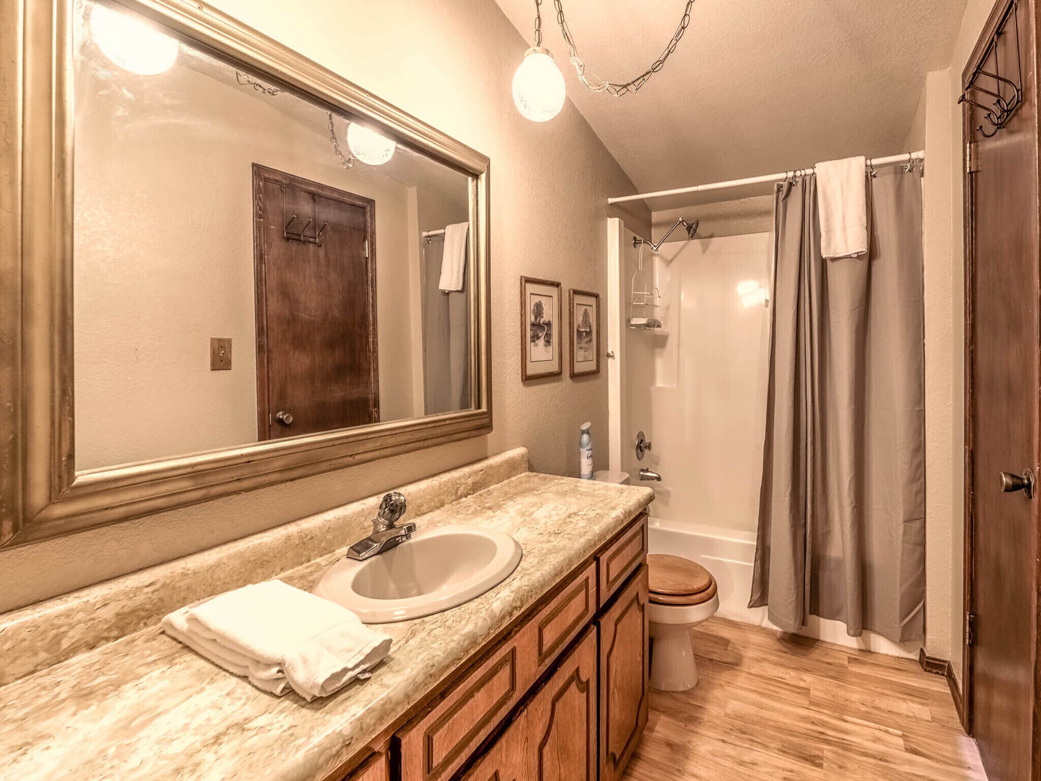 Une salle de bain avec un grand miroir, un lavabo, des toilettes et un espace douche.