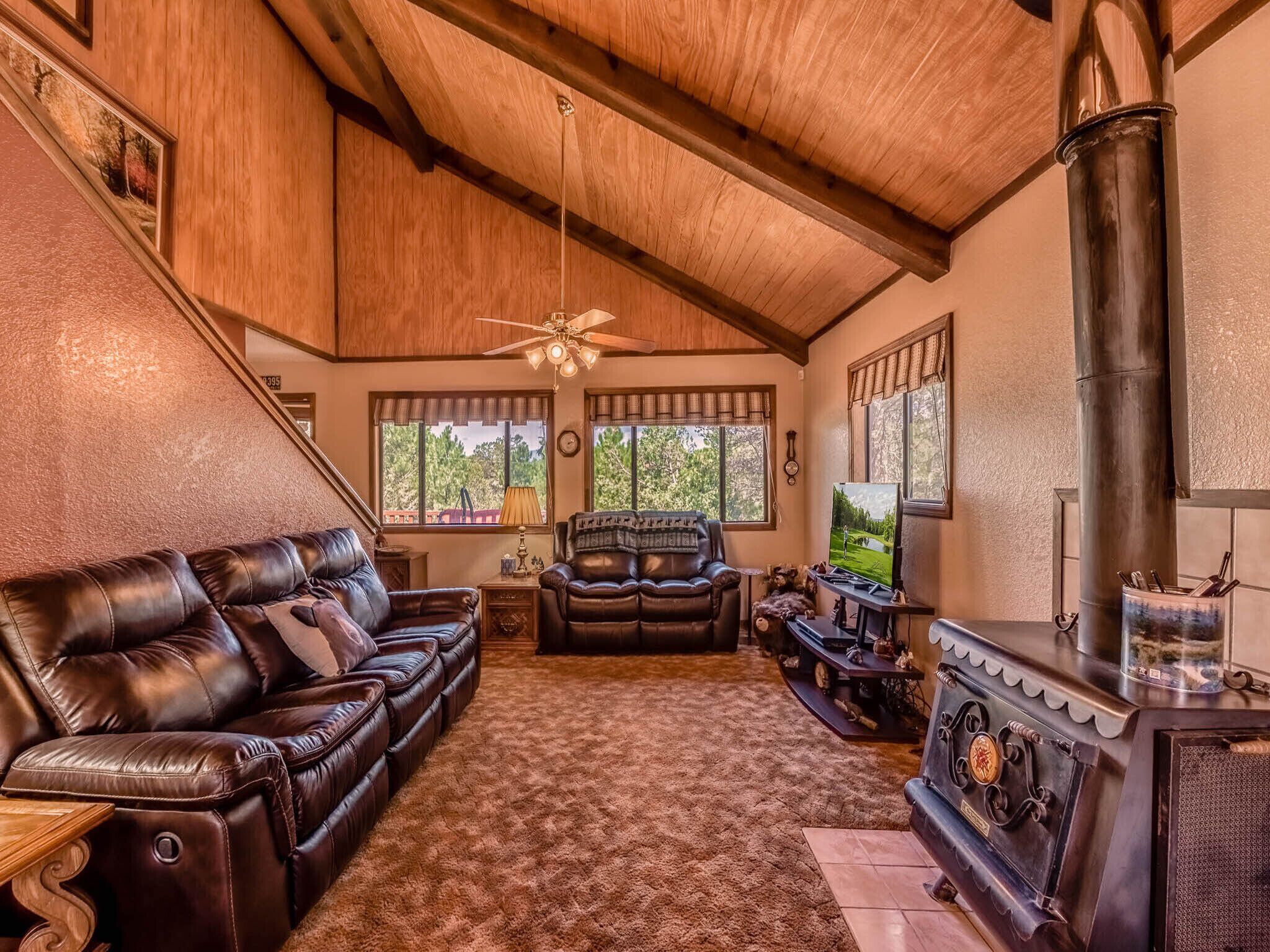 A cozy living room with a fireplace, leather sofa, and a ceiling fan.