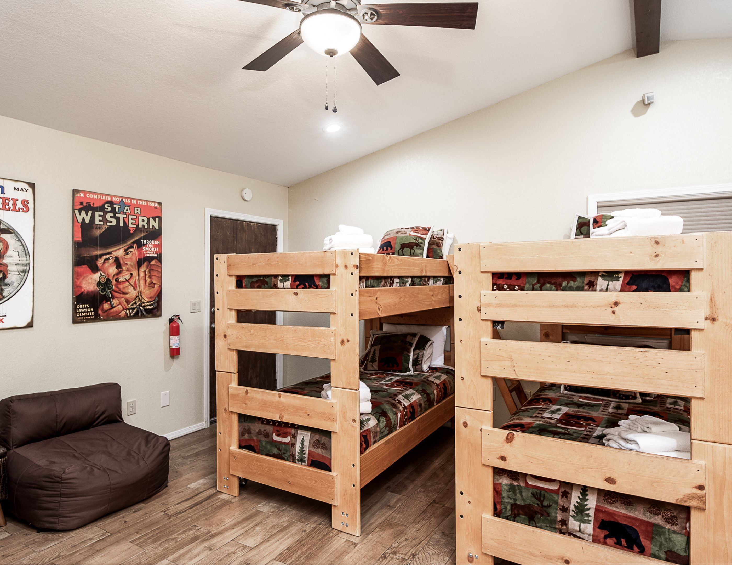 A room with two bunk beds, a brown sofa, a ceiling fan, and posters on the wall.