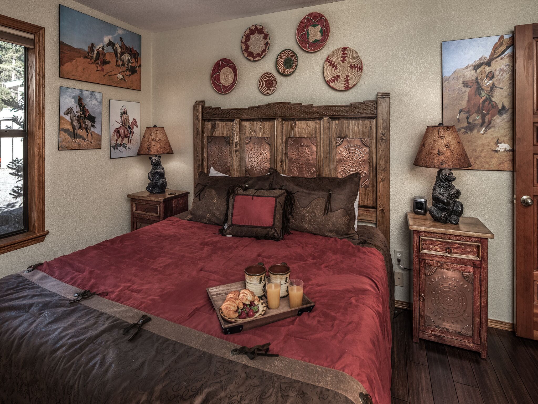 Quarto com cama grande, cabeceira de madeira e bandeja de doces.