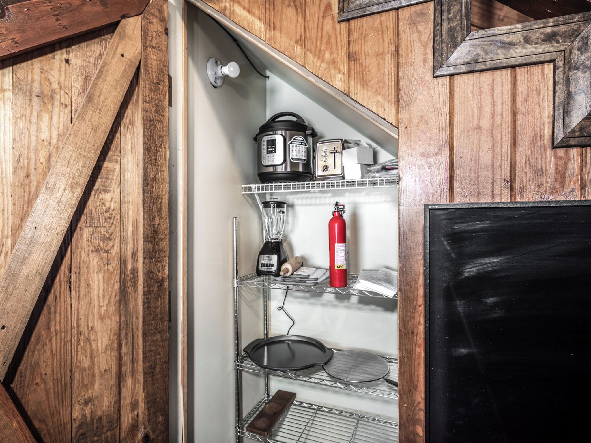 A kitchen with wooden cabinets, a blender, a red fire extinguisher, and a black refrigerator.